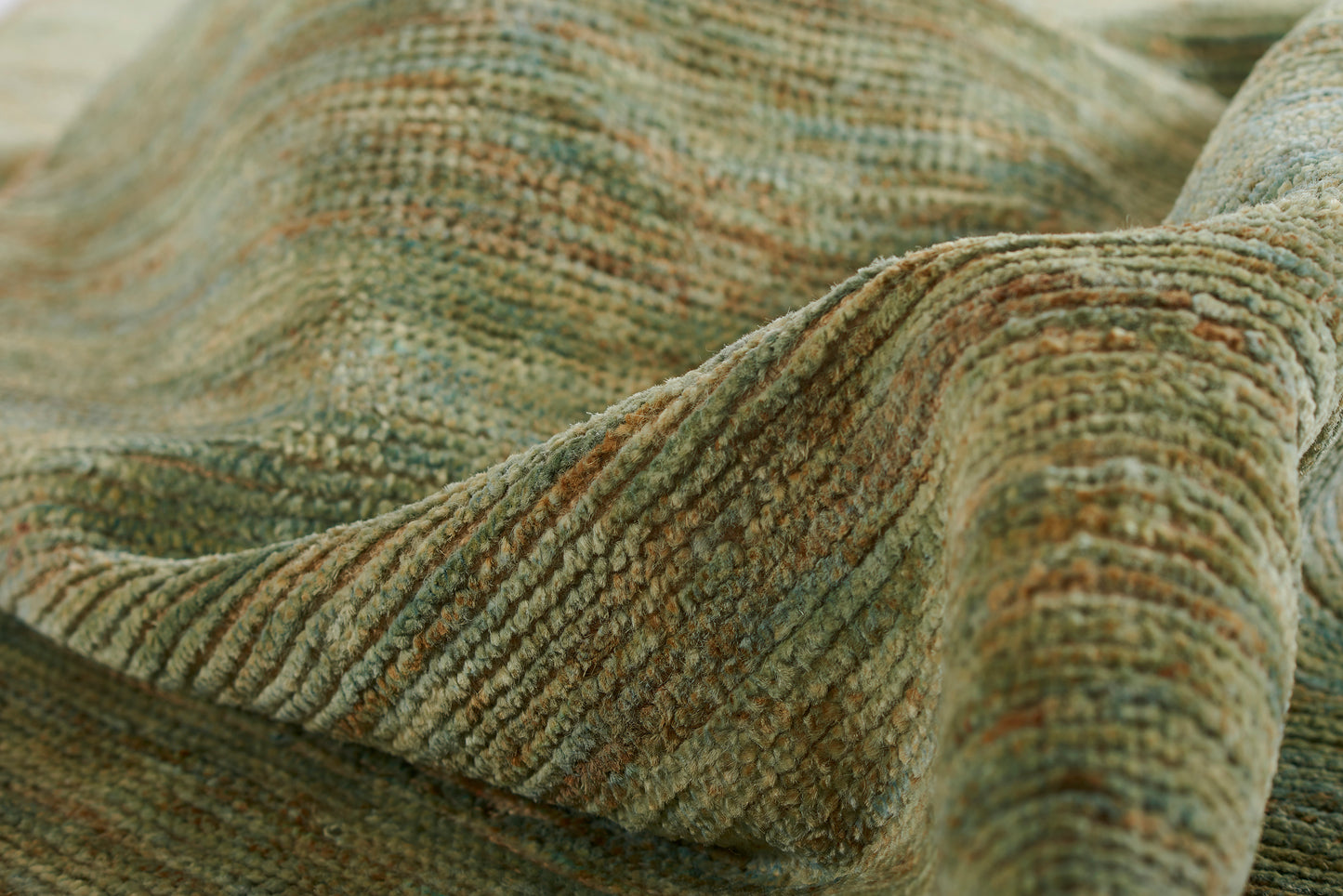Close-up of olive-green and brown variegated woven fabric with a chunky ribbed texture, draped like a blanket.