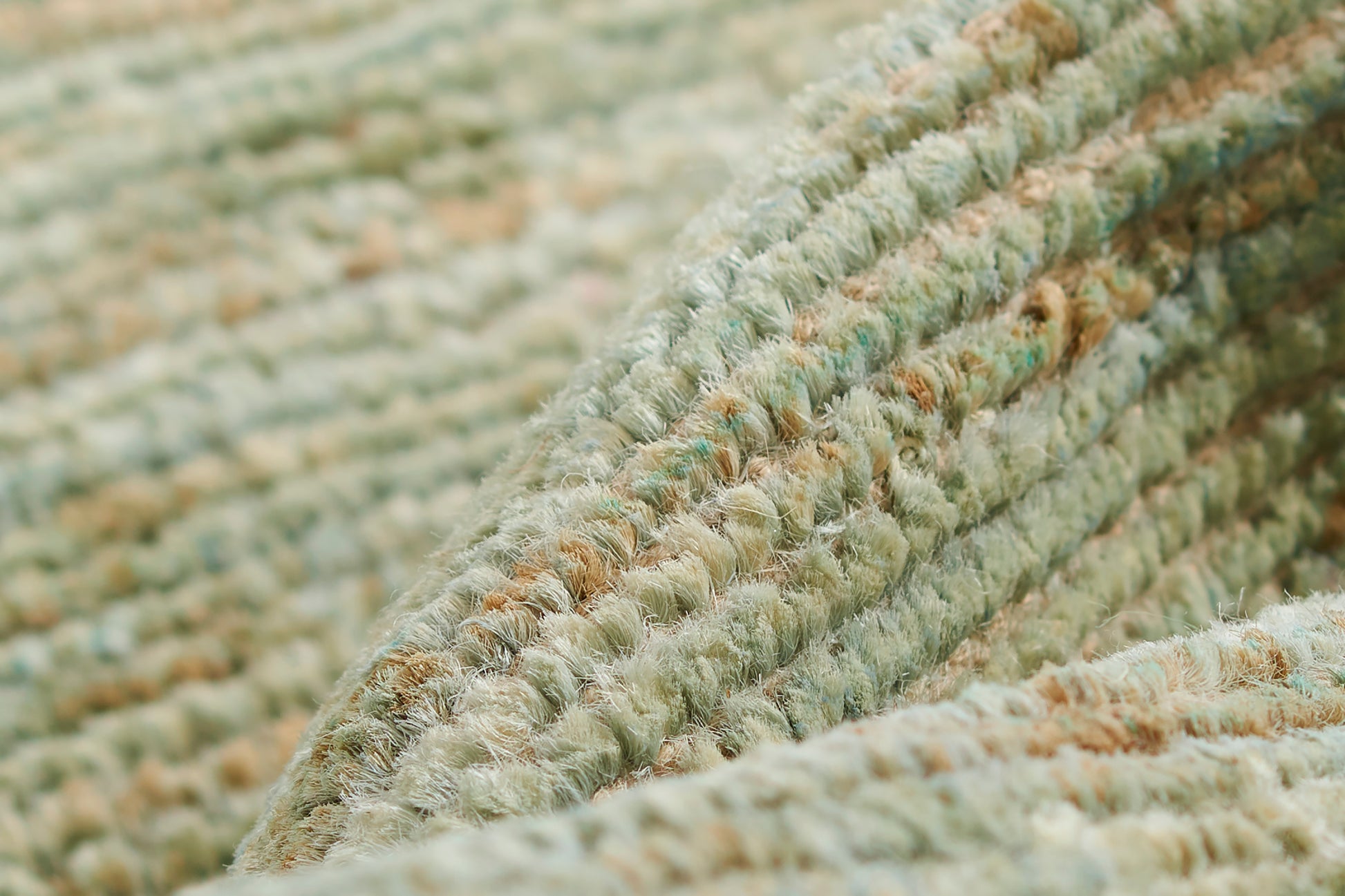 Close-up of a plush green-toned rug with cream and tan speckled loops and thick pile.