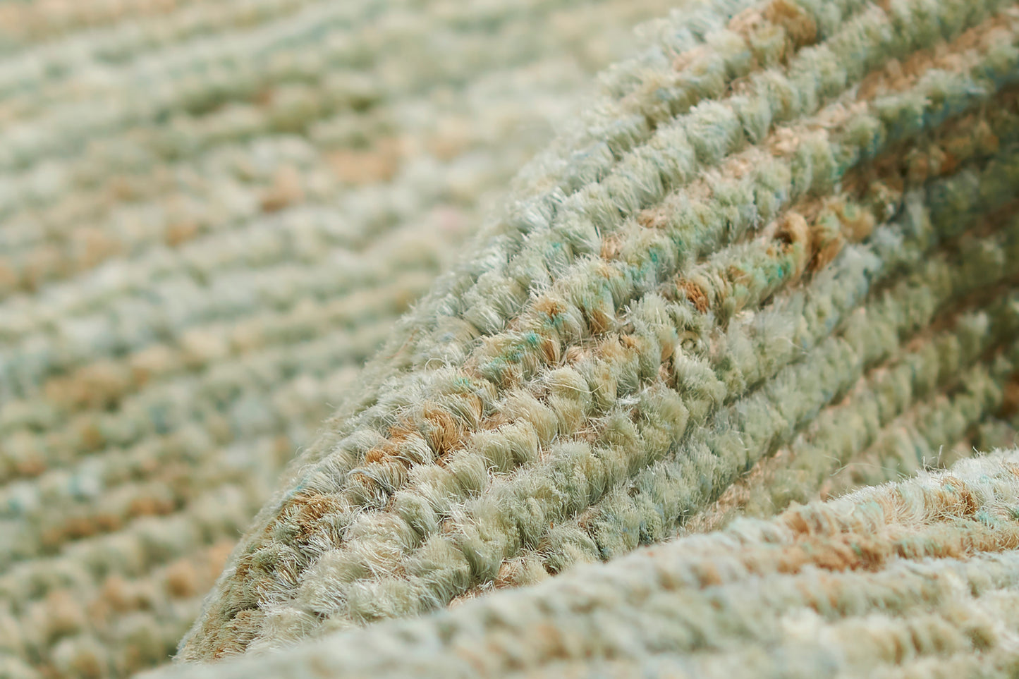 Close-up of a green-toned boucle rug with soft, looped pile in sage and beige tones.