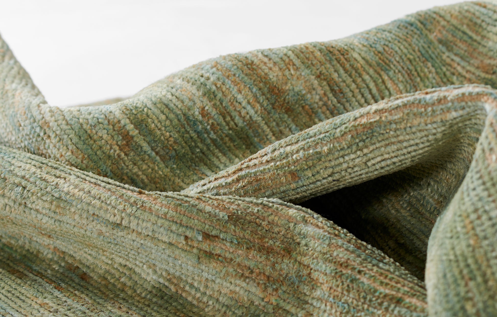 Close-up of green-brown boucle rug fabric with olive/gray tones and soft pile.
