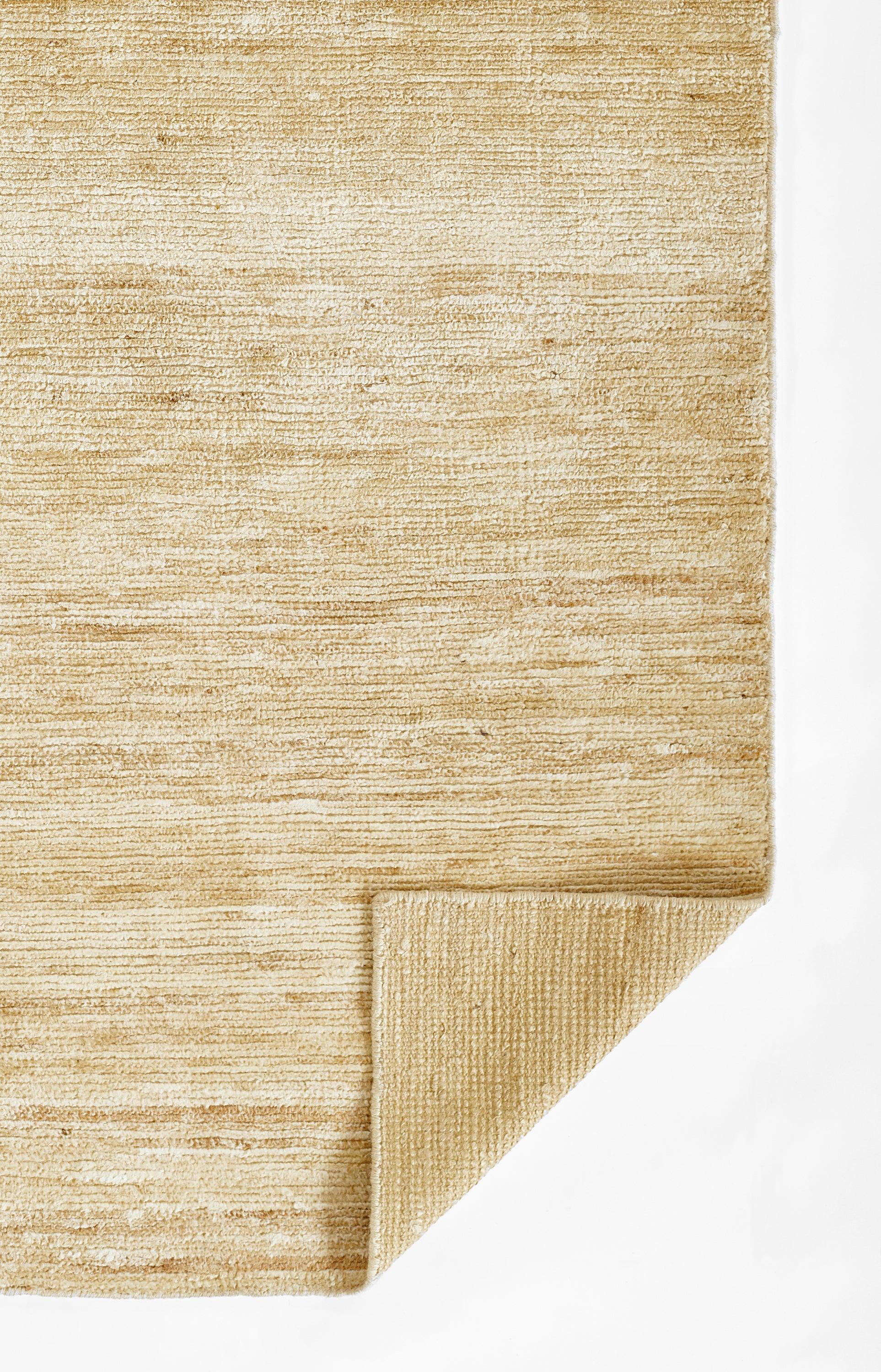 Beige natural fiber rug with woven texture and folded corner detail.
