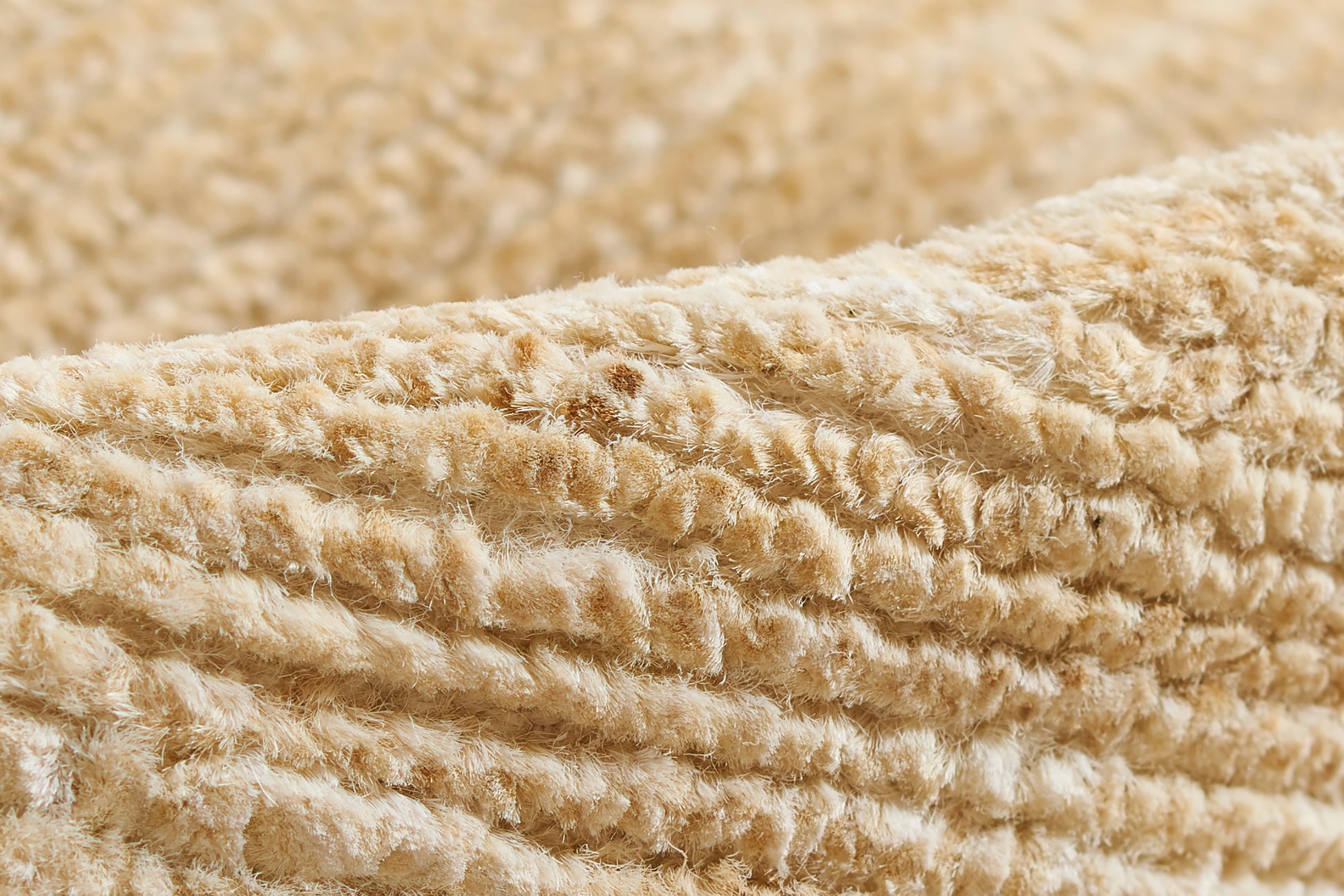 Beige plush sherpa fabric close-up with ribbed texture on a rug