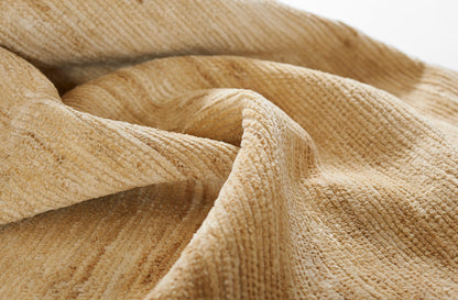 Beige ribbed rug fabric close-up with soft folds; plush, terry-like texture.