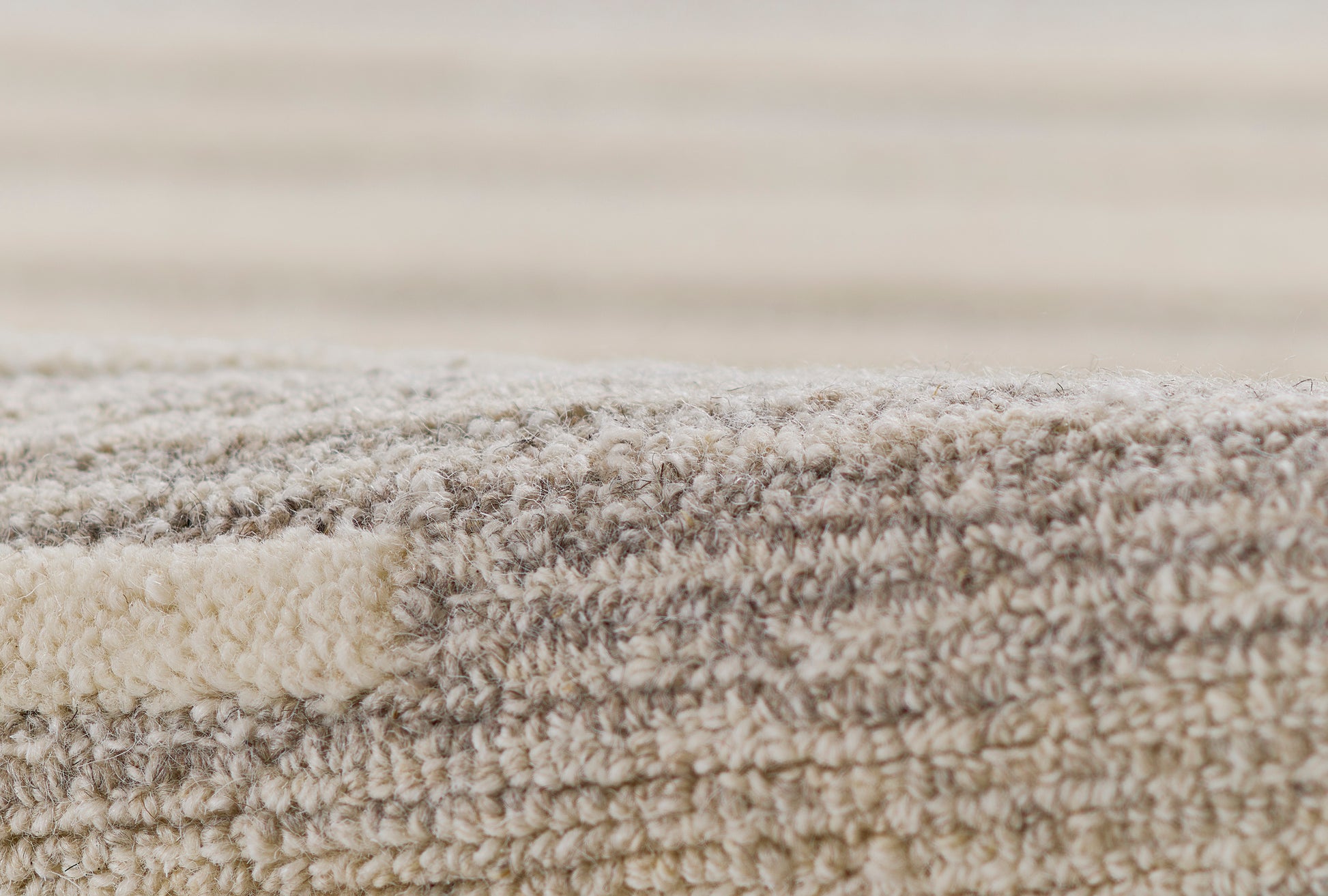 Close-up of beige-gray shag rug with dense, fluffy pile and soft plush texture.