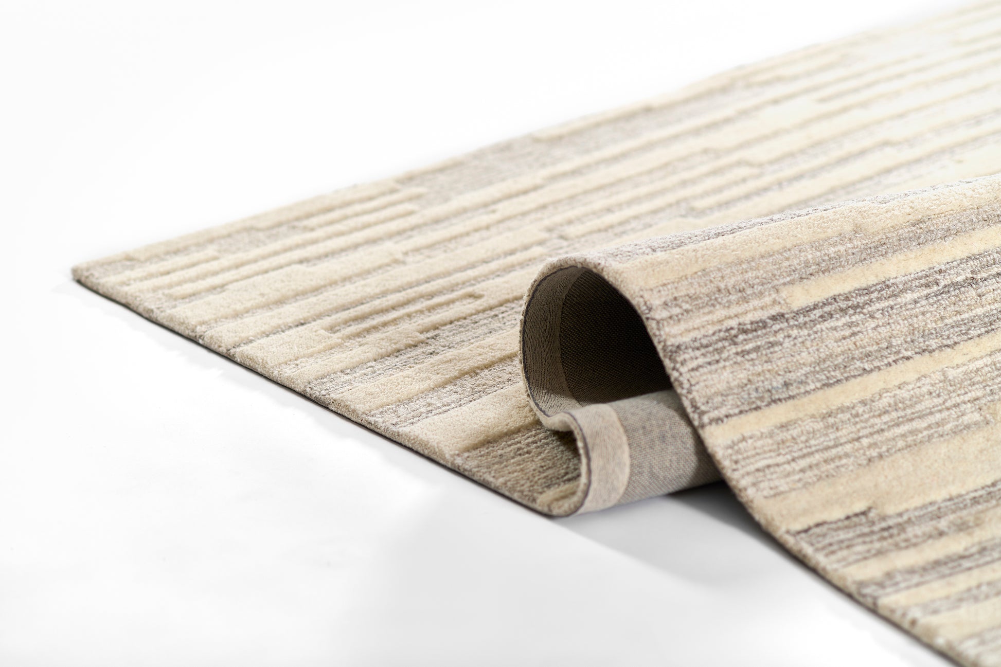 Beige and gray striped woven area rug partially rolled at the edge.