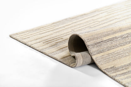 Beige and gray striped woven area rug partially rolled at the edge.