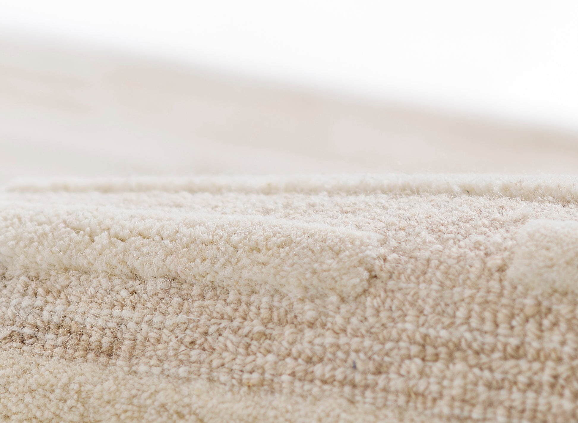 Taupe beige plush rug close-up showing dense soft pile and textured surface.