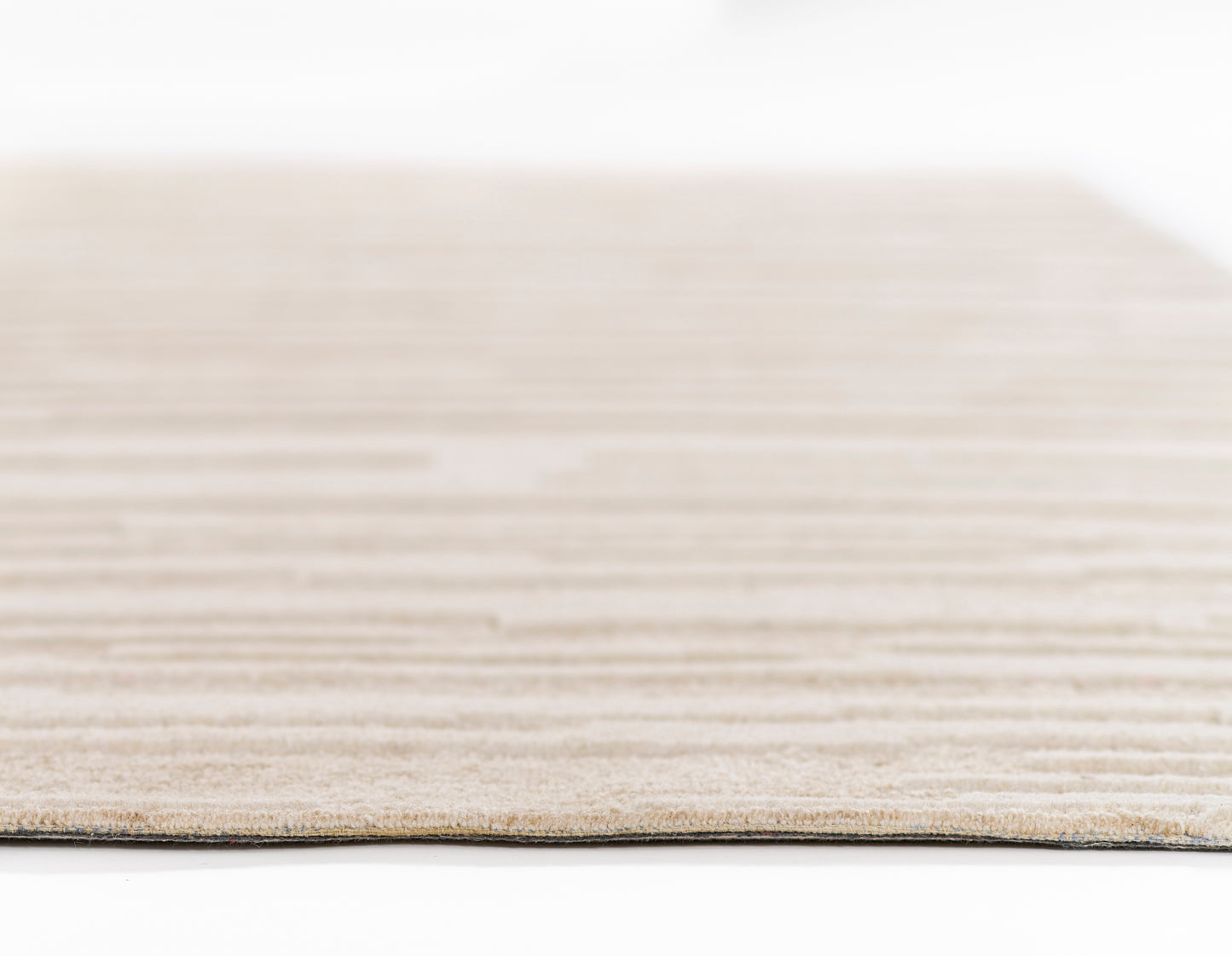 Taupe flat-weave rug edge, close-up with subtle horizontal texture on white background.