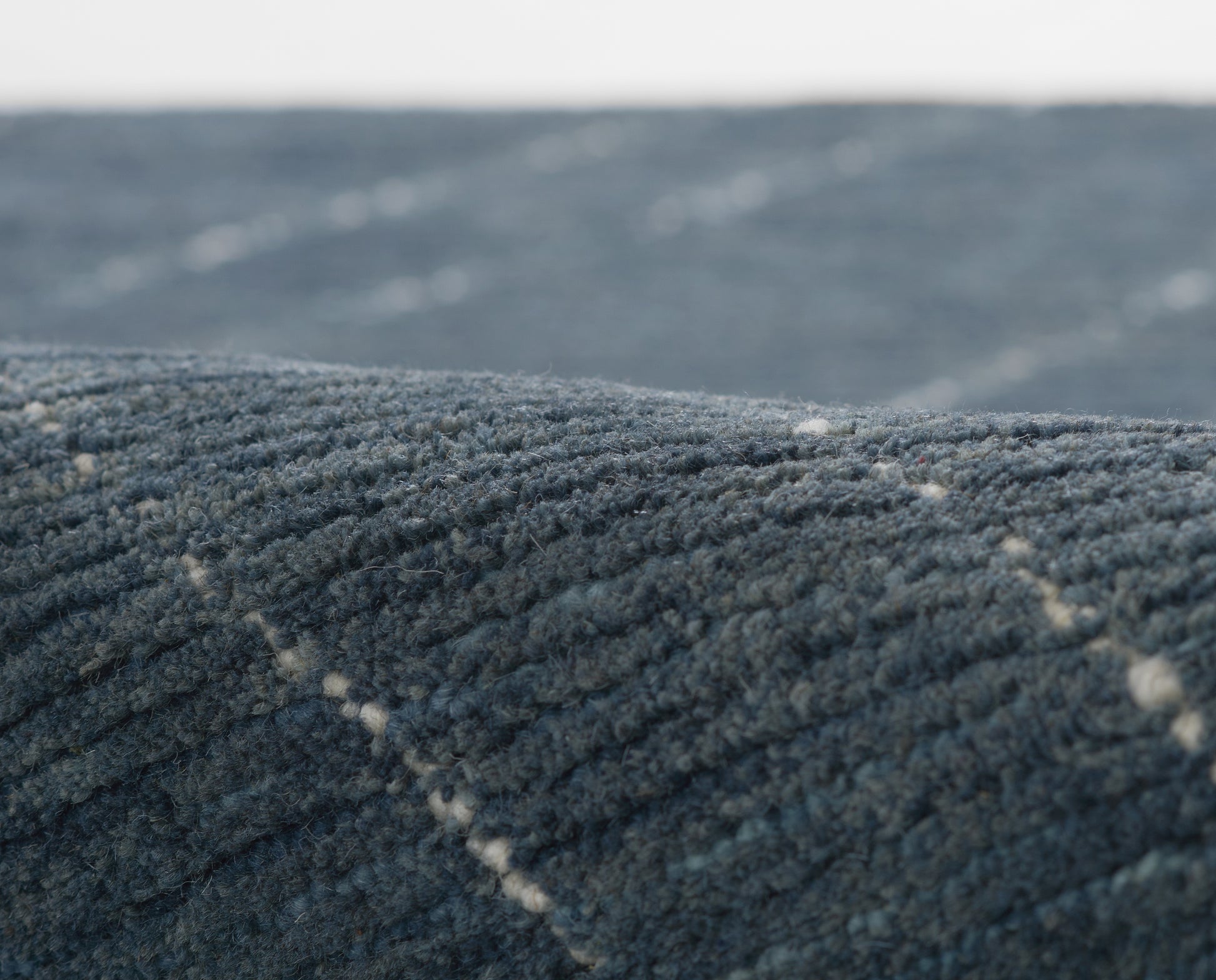 Close-up of dark blue plush carpet with ribbed tufting and subtle diagonal stitching.