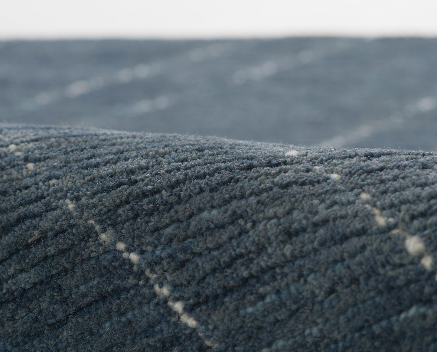 Close-up of dark blue textured carpet with ridged plush pile and subtle diagonal lines.