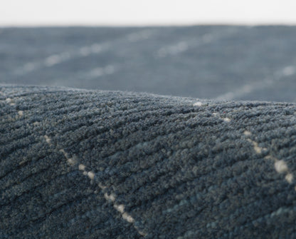 Close-up of dark blue textured carpet with ridged plush pile and subtle diagonal lines.