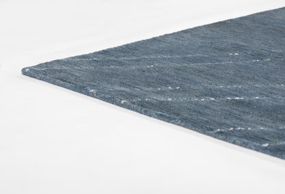 Blue flat-weave rug, 5' x 8', with subtle lighter stripes and textured finish; corner edge visible.