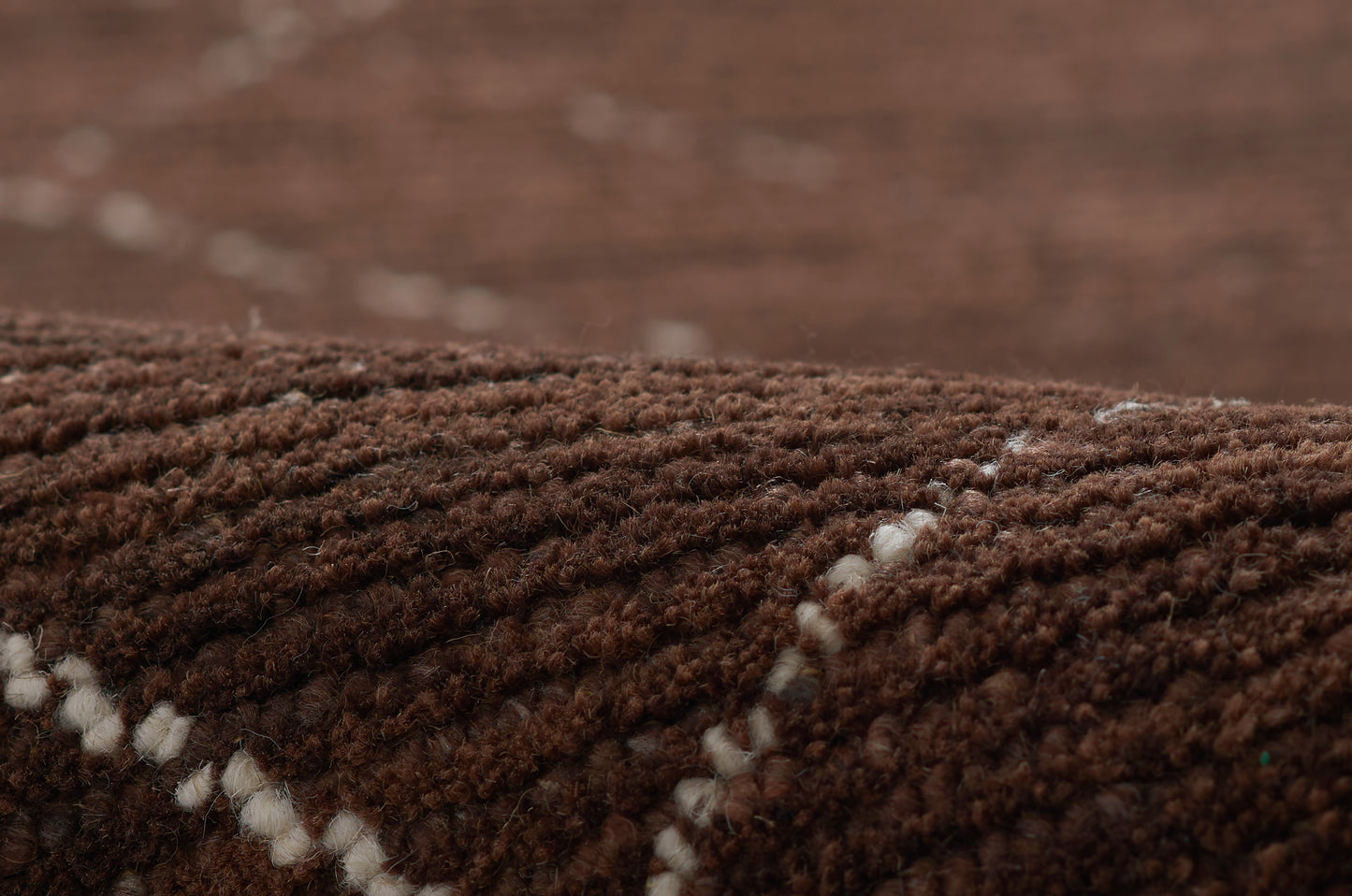 Brown shag rug with thick pile and white stitched diagonal lines creating a linear pattern.
