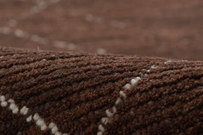Close-up of brown plush rug with white diagonal stitched lines, soft textured rug for home decor.