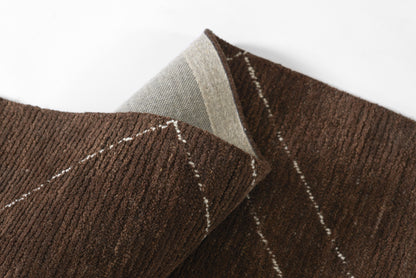 Close-up of brown textured woven fabric with white stitched lines, folded to reveal a gray underside.