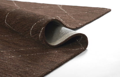 Brown textured rug with a curled corner, showing grey underside and white stitched lines.