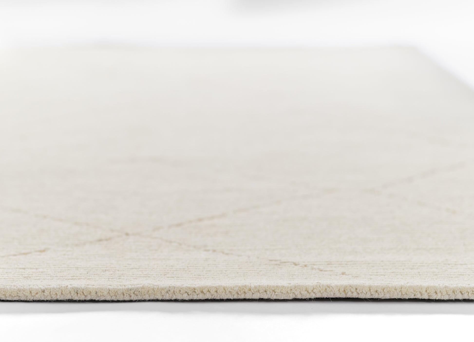 Ivory flat-weave rug with light beige color and visible edge fibers.