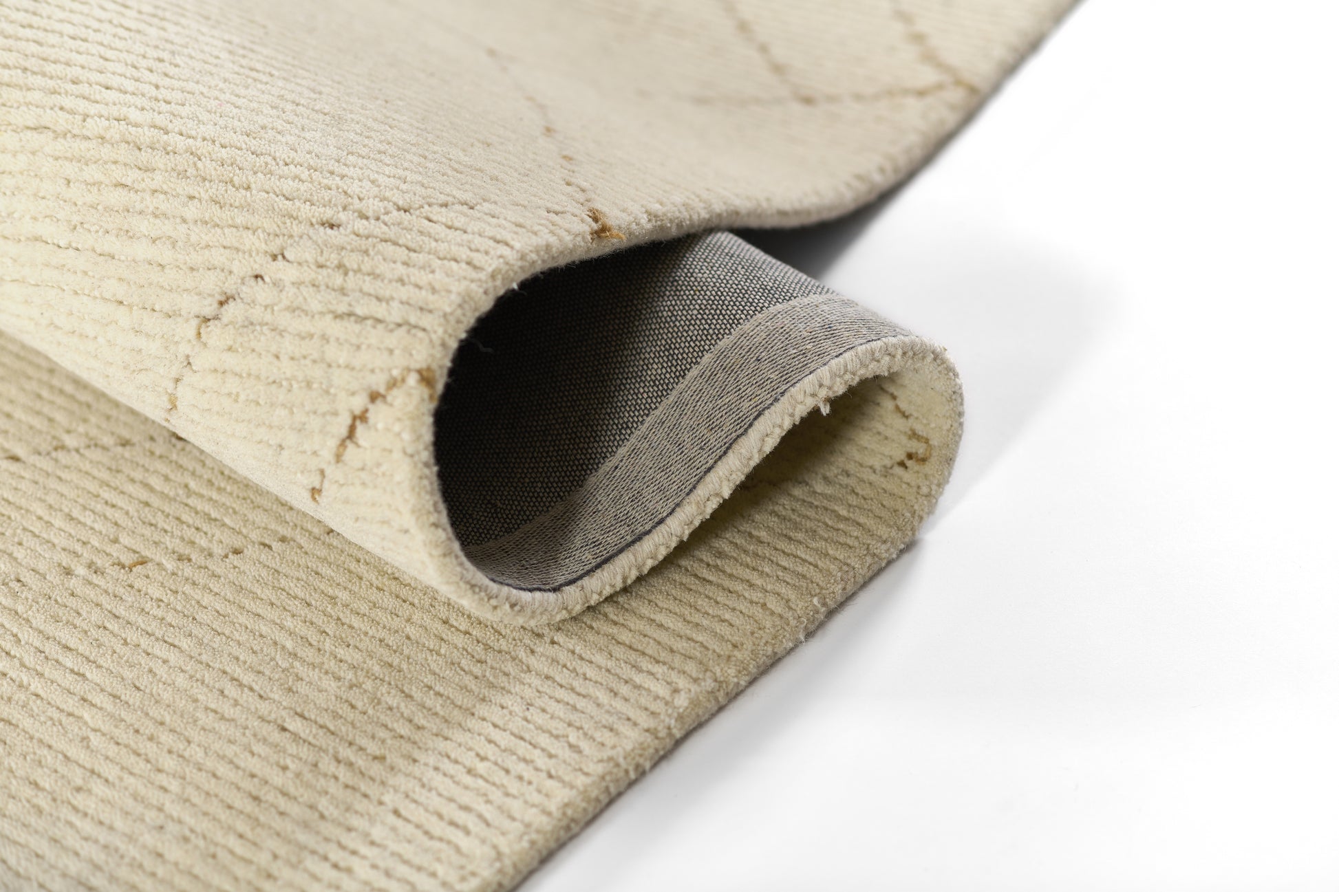Beige woven rug with rolled edge, exposing gray underside and textured loop pile.