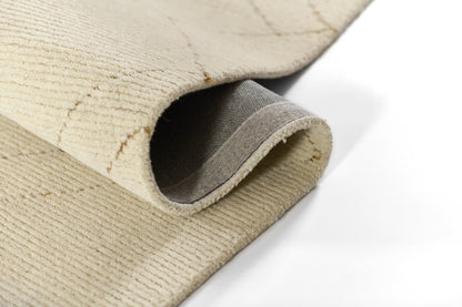 Beige woven rug with rolled edge, exposing gray underside and textured loop pile.