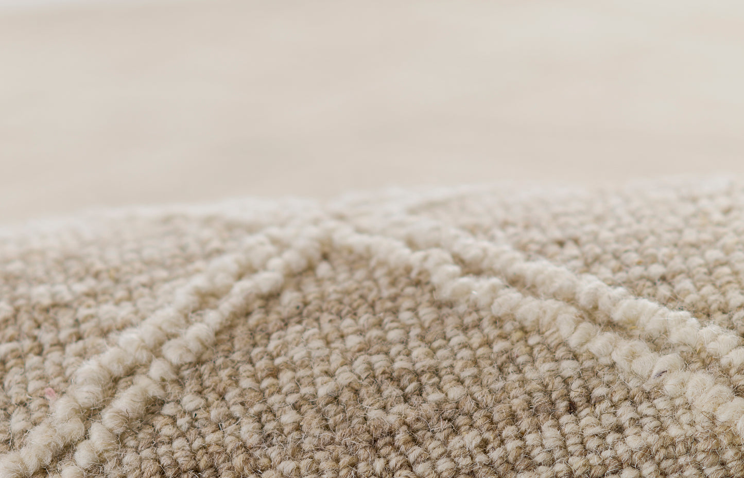 Beige textured woven rug close-up with looped pile and soft natural fibers.