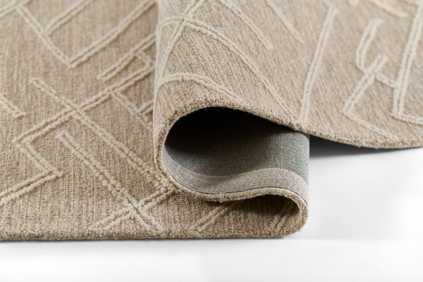 Natural beige textured area rug with geometric pattern and rolled edge, gray underside visible.