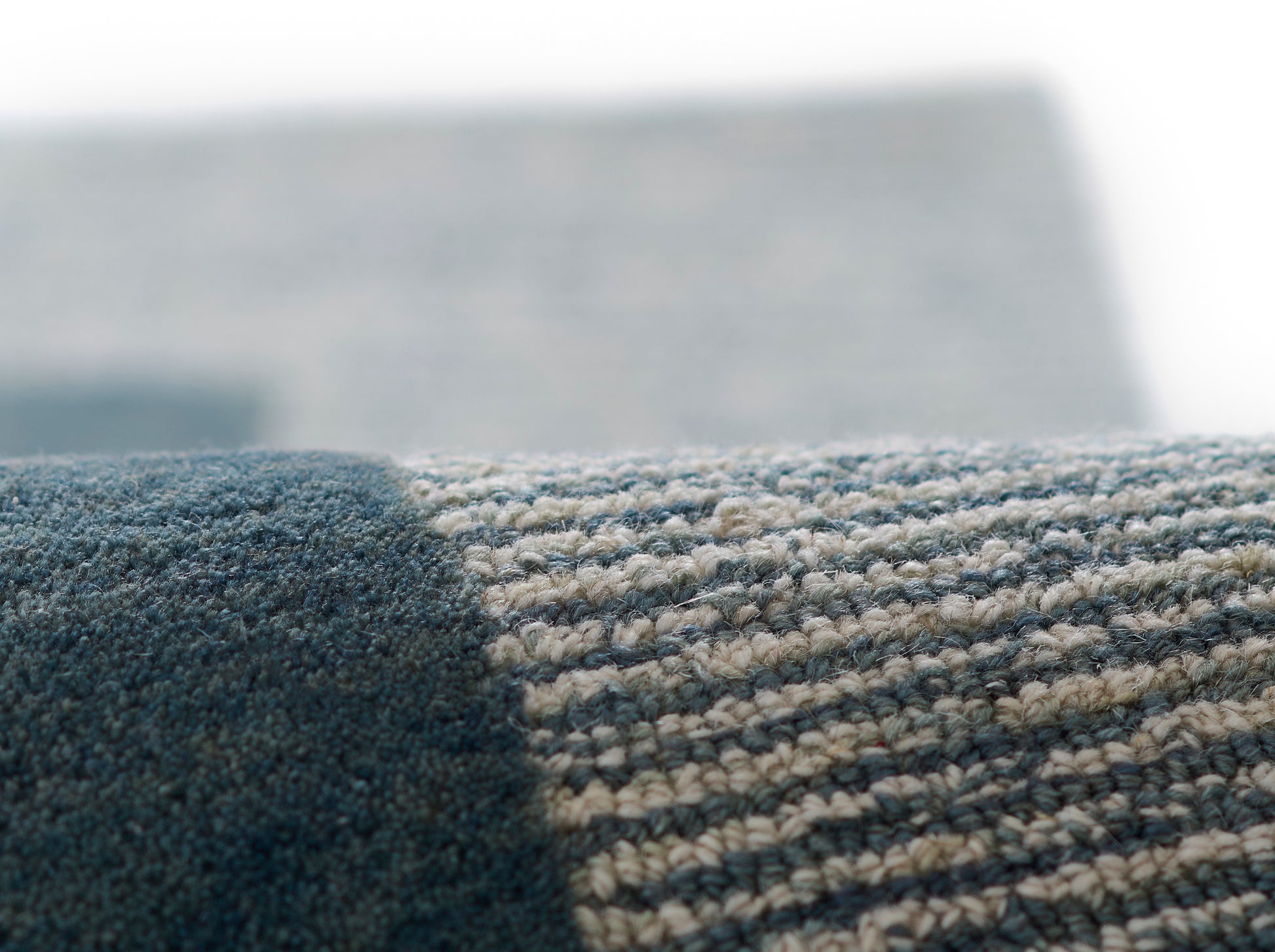 Close-up of a blue & beige striped woven rug with a dark blue border & textured loop pile.