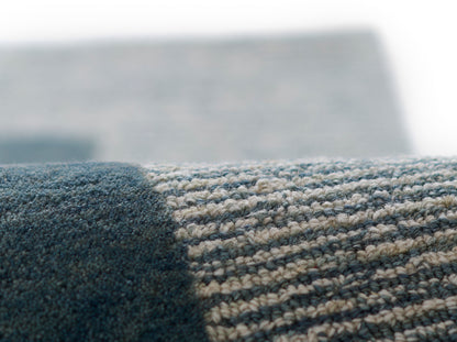 Close-up of blue and beige striped woven rug with navy edge; dense textured pile for casual living spaces.