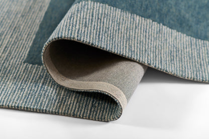 Blue striped woven rug with rolled edge, showcasing denim-blue tones and beige backing.