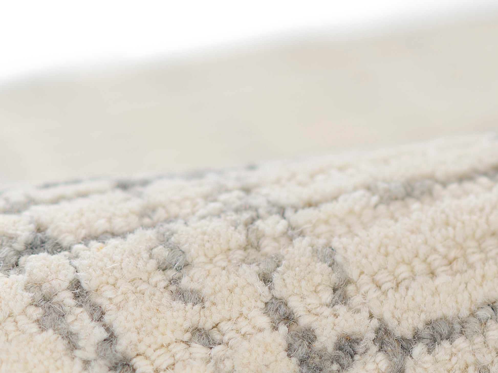 Close-up of a cream & gray patterned rug with plush, shag-like pile & soft geometric motifs.