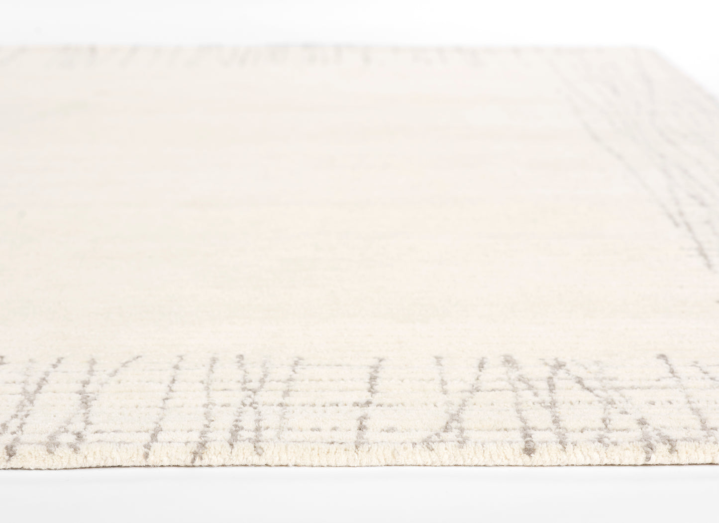 Rectangular cream flat-weave rug with a light taupe border motif; soft, neutral home decor.