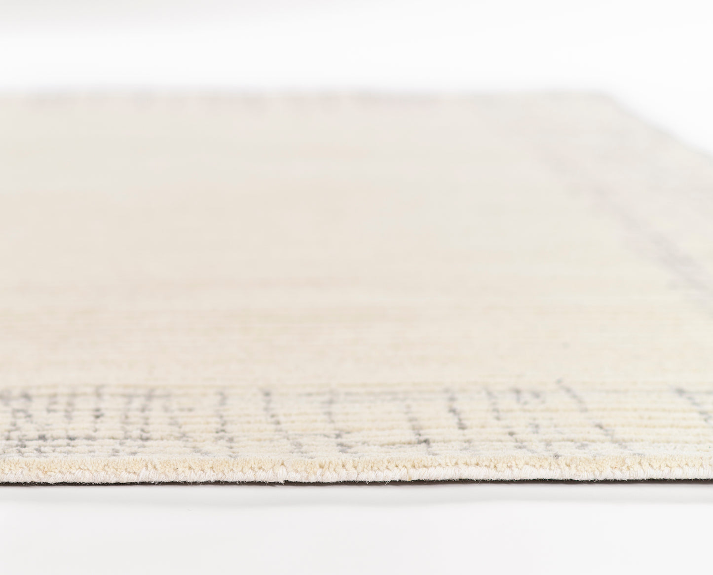 Beige woven rug with a subtle border, rectangular shape, soft pile for living room or bedroom decor.