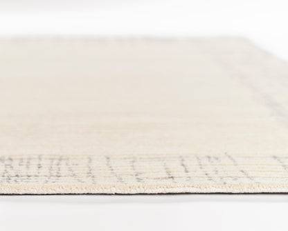 Beige woven rug with a subtle border, rectangular shape, soft pile for living room or bedroom decor.