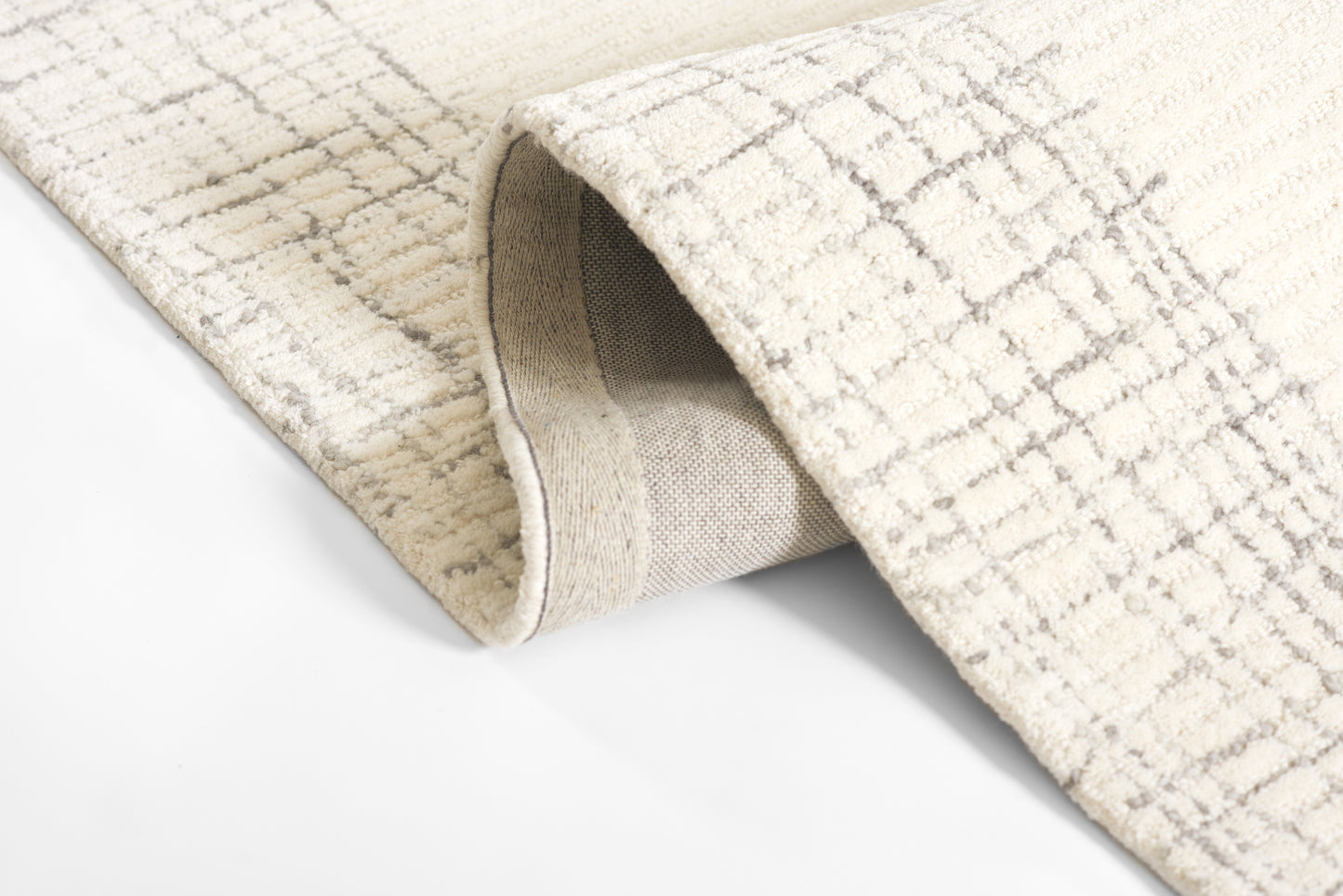 Beige textured woven rug with a subtle gray grid pattern and folded edge, 9' x 12'.