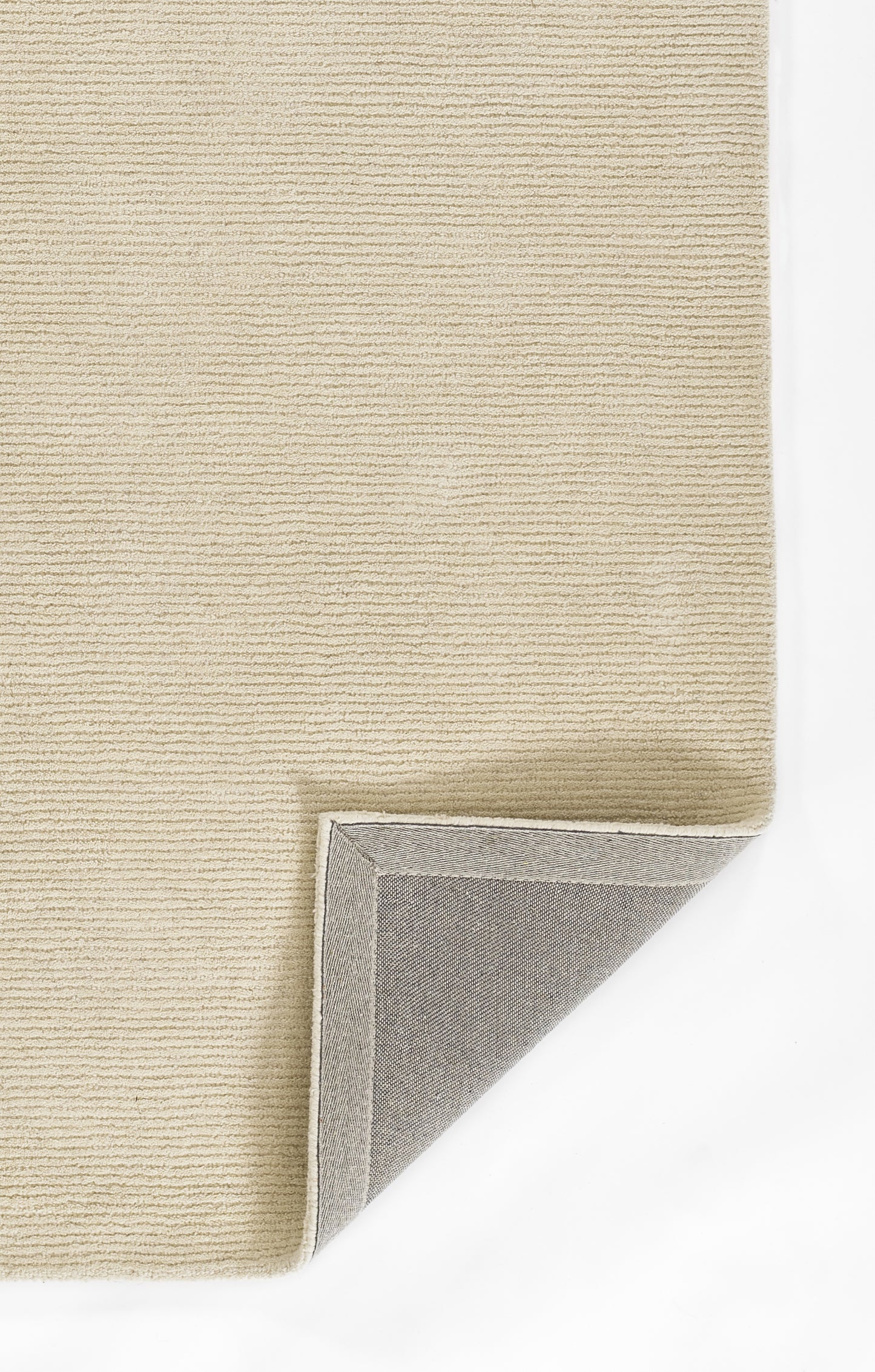 Beige ribbed rug with folded corner showing grey underside; neutral, modern floor decor.