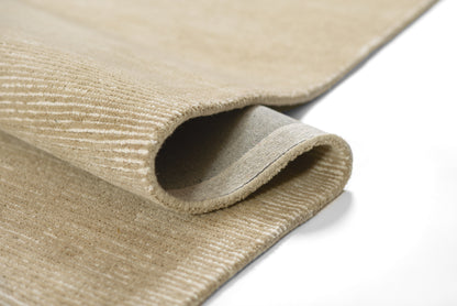 Taupe textured rug with ribbed pile and folded edge for cozy neutral decor.