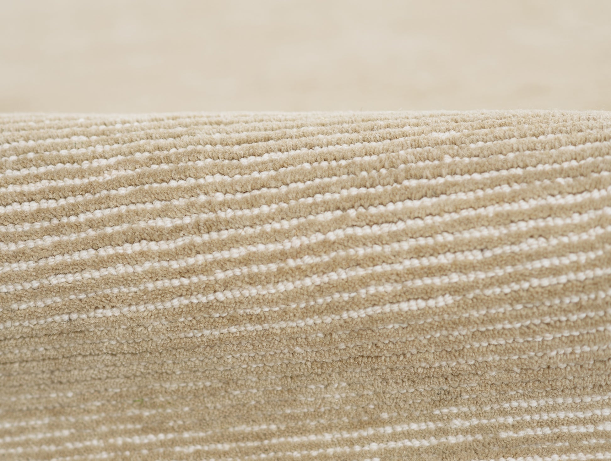 Beige textured rug close-up with cream horizontal stripes in woven pile; neutral, modern decor.