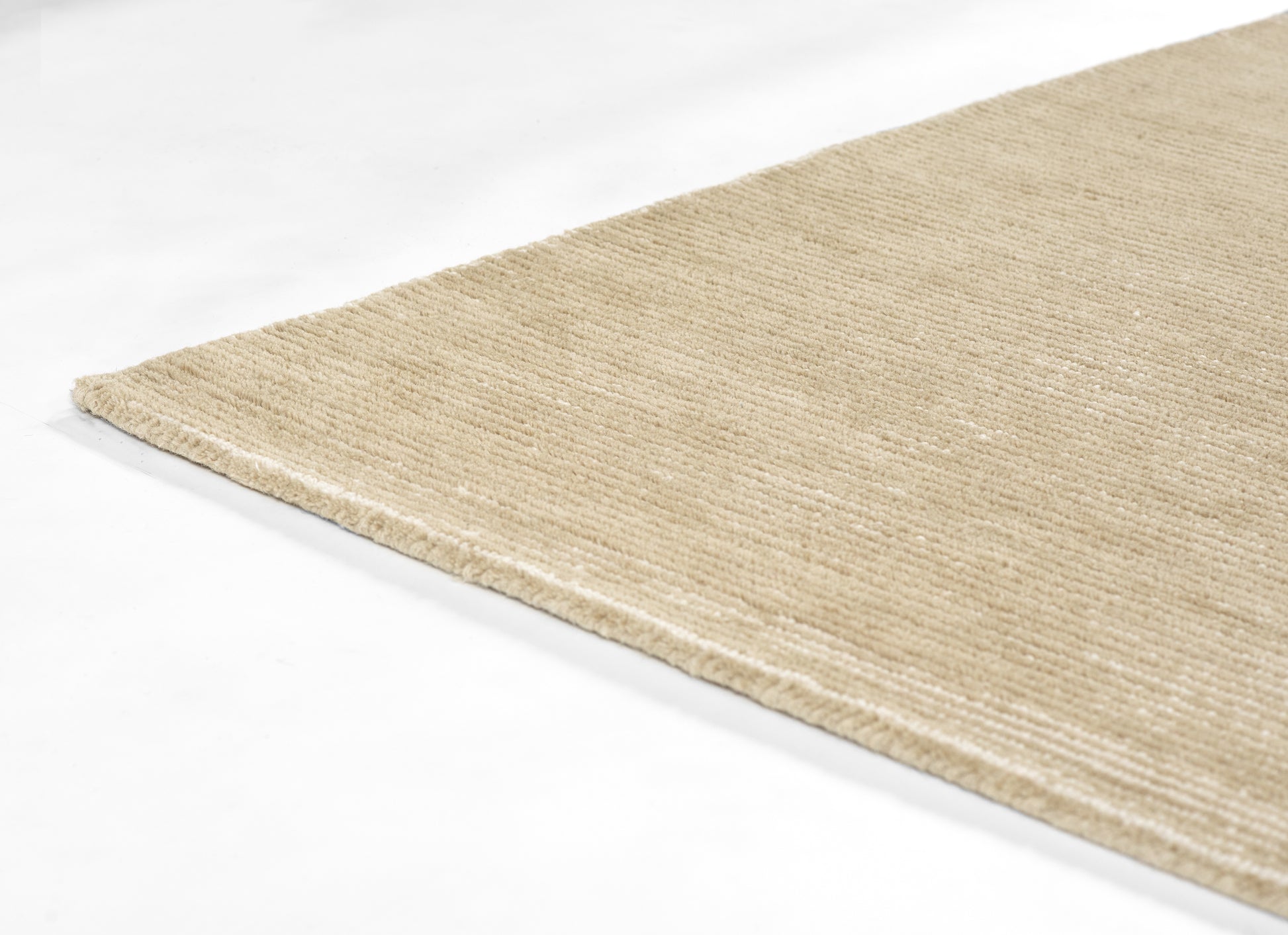 Beige natural-fiber rug edge close-up; woven jute/sisal, rectangular, rustic style for living room or entryway