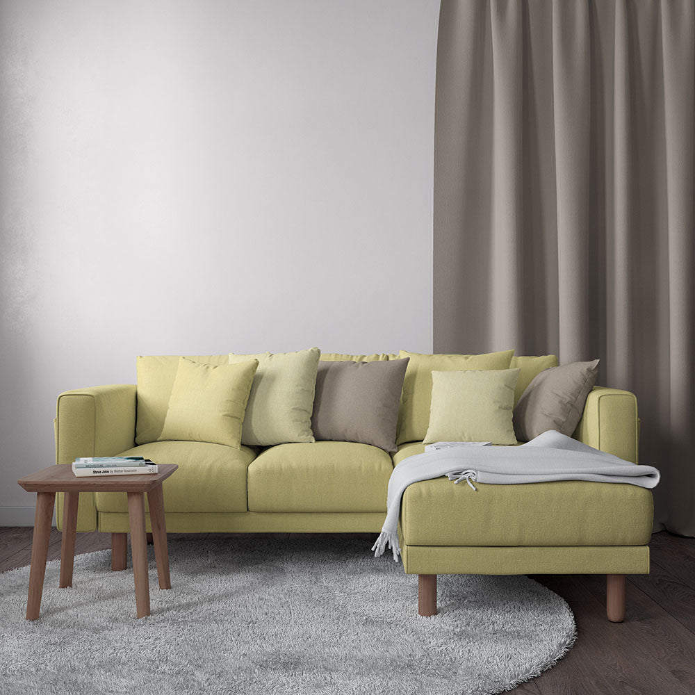 Butter-yellow fabric sectional sofa with chaise, neutral cushions, wooden legs, gray rug, and round wood coffee table.