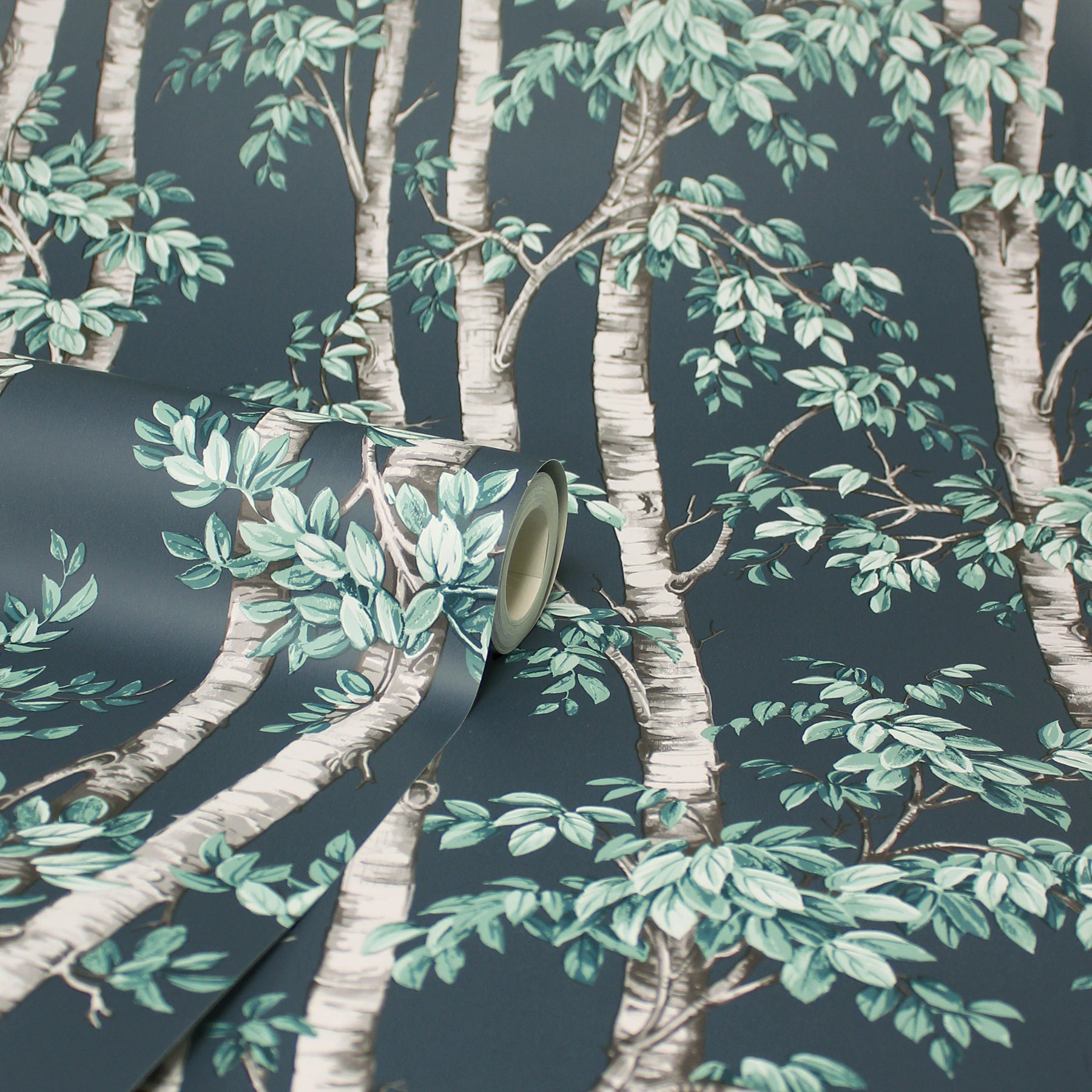 Wallpaper roll featuring blue trees on a dark teal background, partly unrolled.
