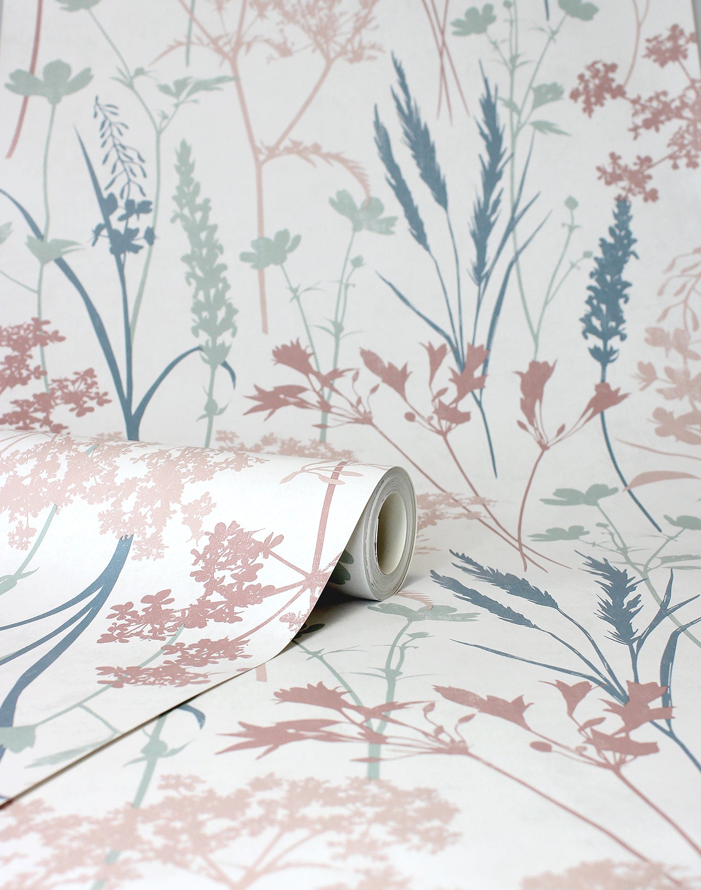 Rolled botanical wallpaper sample with pastel pink, blue & teal grasses & flowers on a pale backdrop.