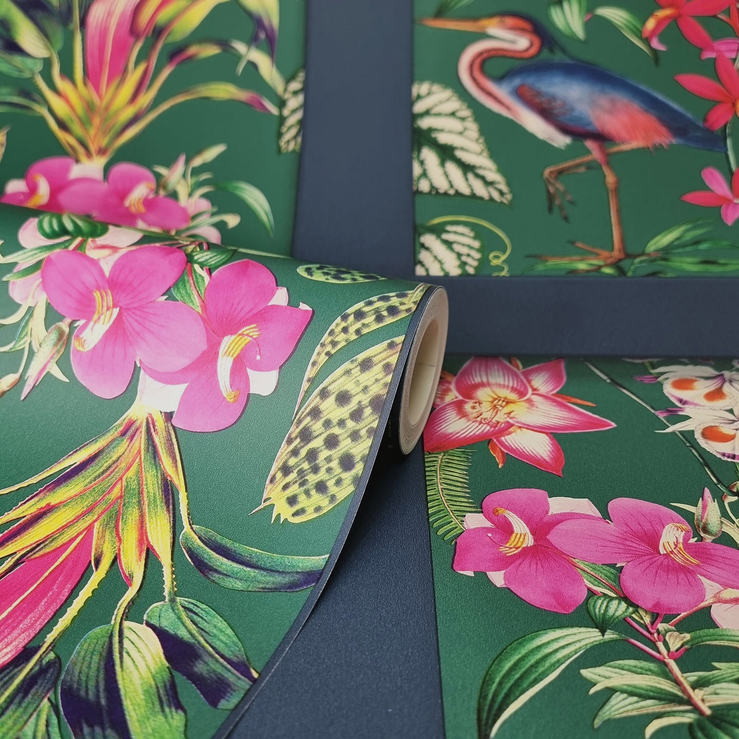 Rolled tropical wallpaper with green background, pink orchids, lush leaves and colorful birds in a vibrant botanical print.