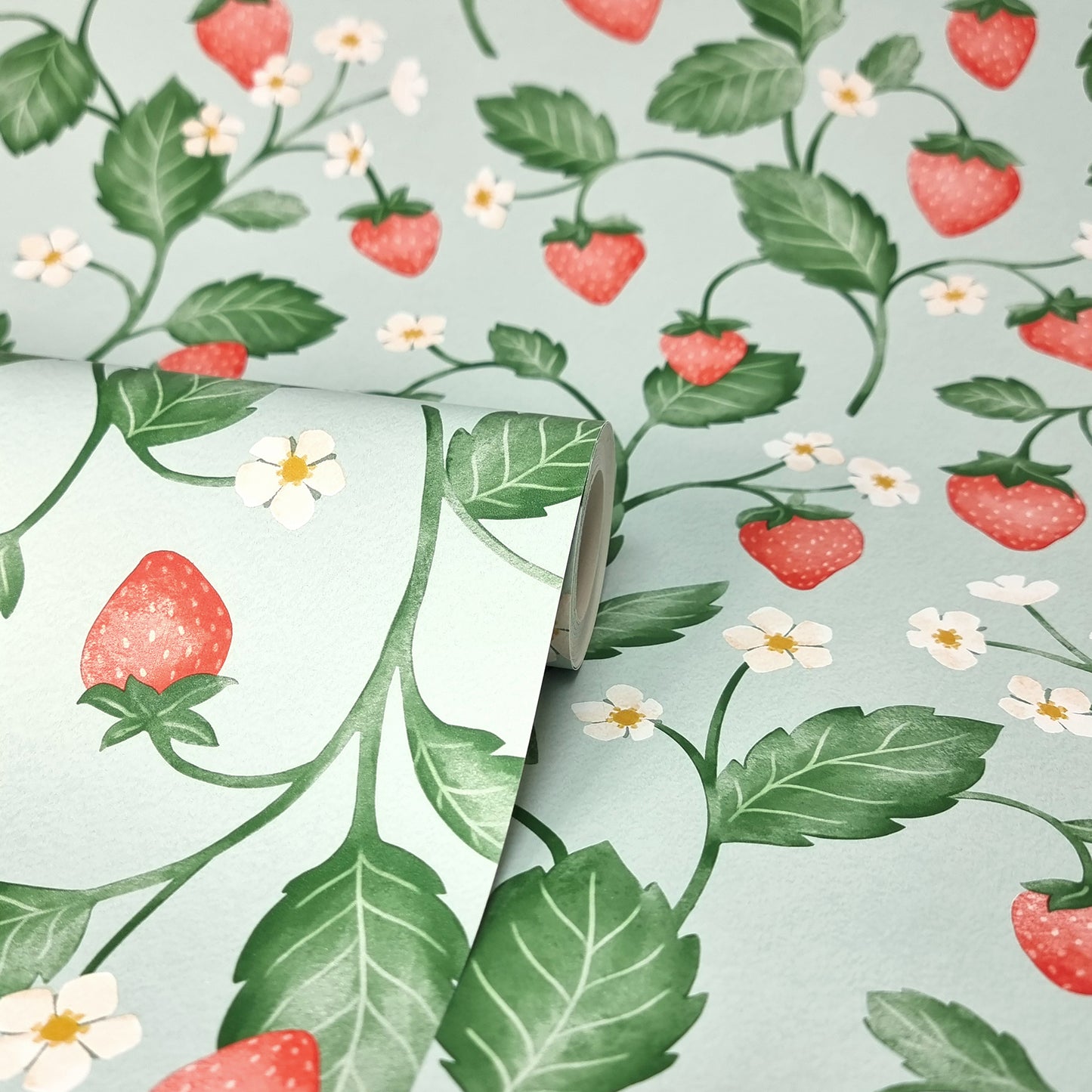 Close-up of a strawberry vine pattern on seafoam wallpaper, with red berries, green leaves and white flowers.