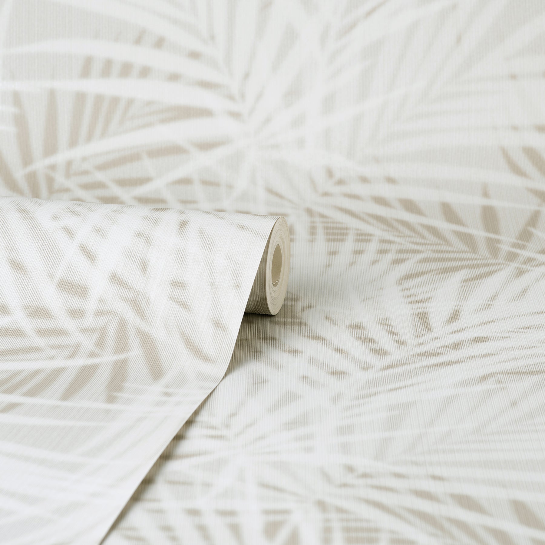 Beige wallpaper roll with white palm leaf pattern; tropical, contemporary wall decor, rolled at edge.