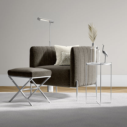 Brown curved fabric sofa with matching ottoman on chrome legs, modern side table with vases and a bird sculpture.