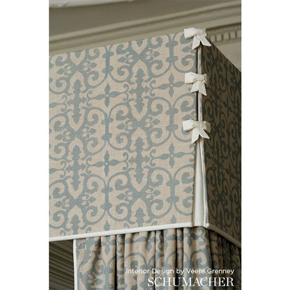 Damask patterned lilac and cream fabric-covered storage ottoman with white bow accents and a pleated skirt.