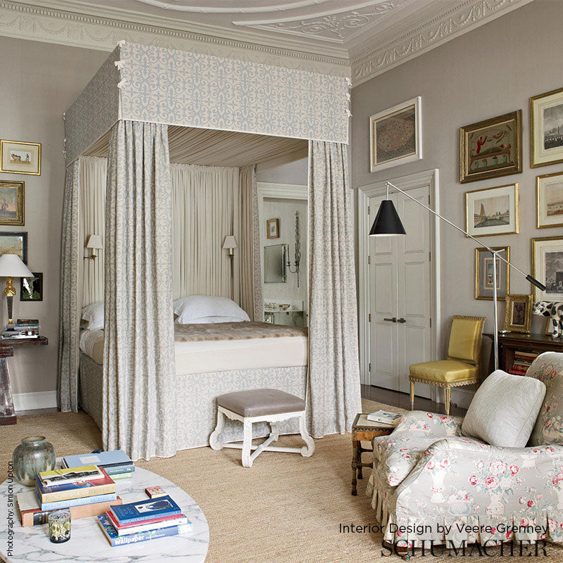 Gallery wall of lilac fern prints in a refined bedroom, with a four-poster bed, light patterned drapes, and neutral bedding.