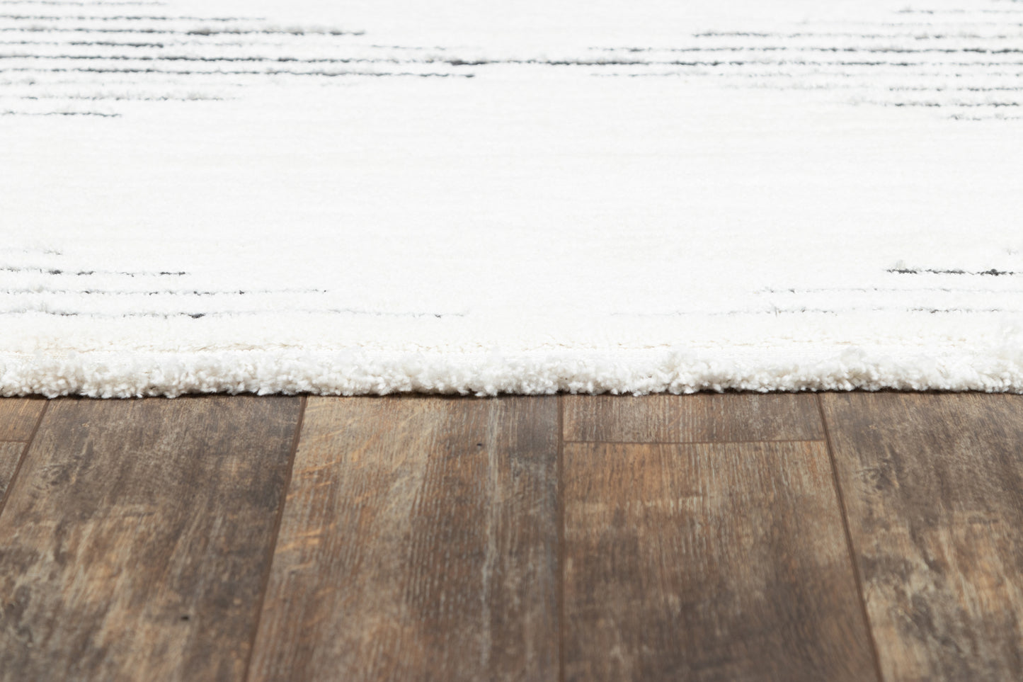 White textured rug on a dark brown hardwood floor.