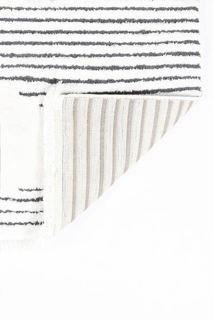 Soft white shag rug with dark gray horizontal stripes; folded corner shows cream ribbed underside.