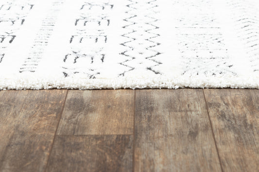 White shag rug with black geometric patterns on a dark brown wooden floor