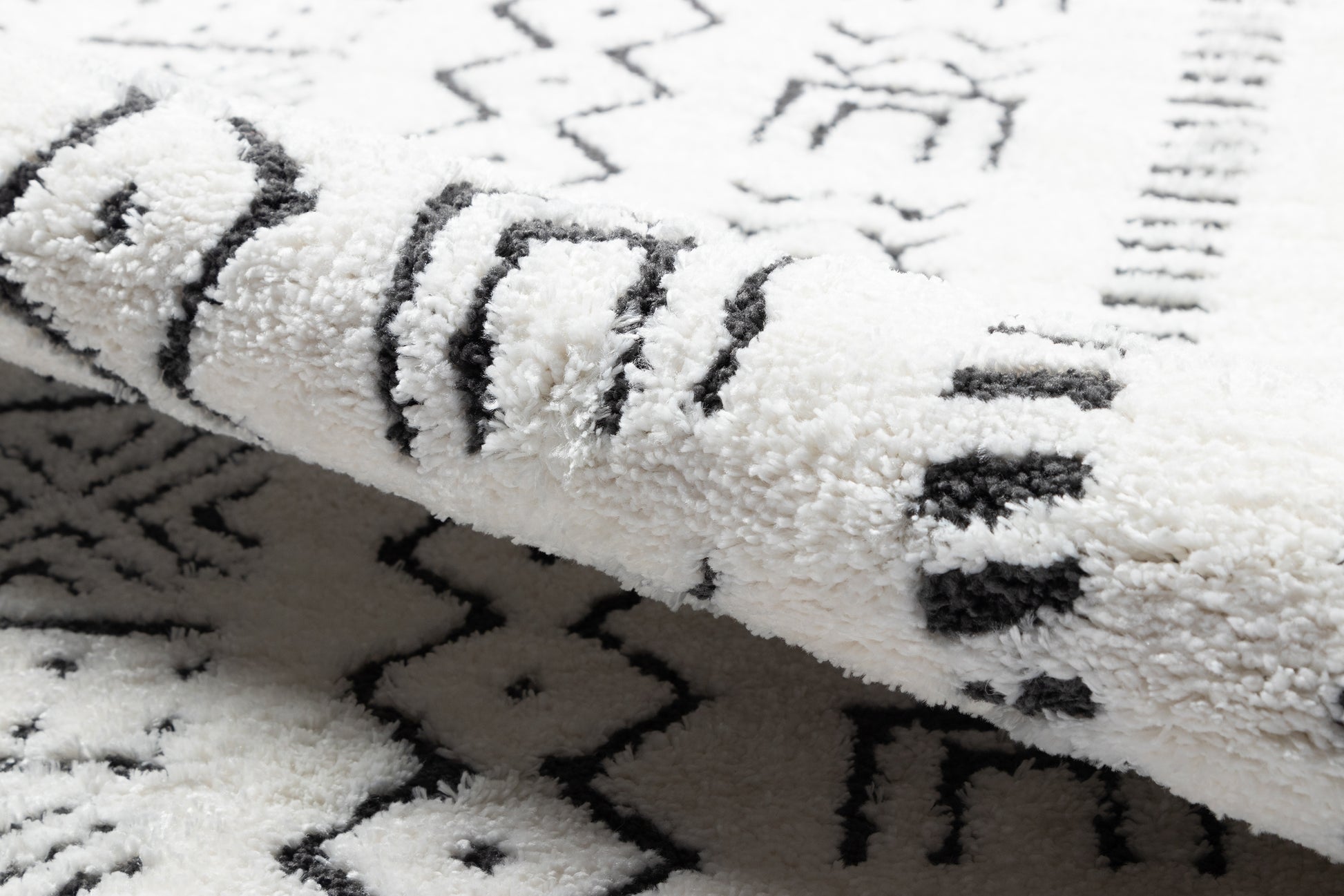 White shag rug with black geometric tribal pattern and soft, fluffy pile.